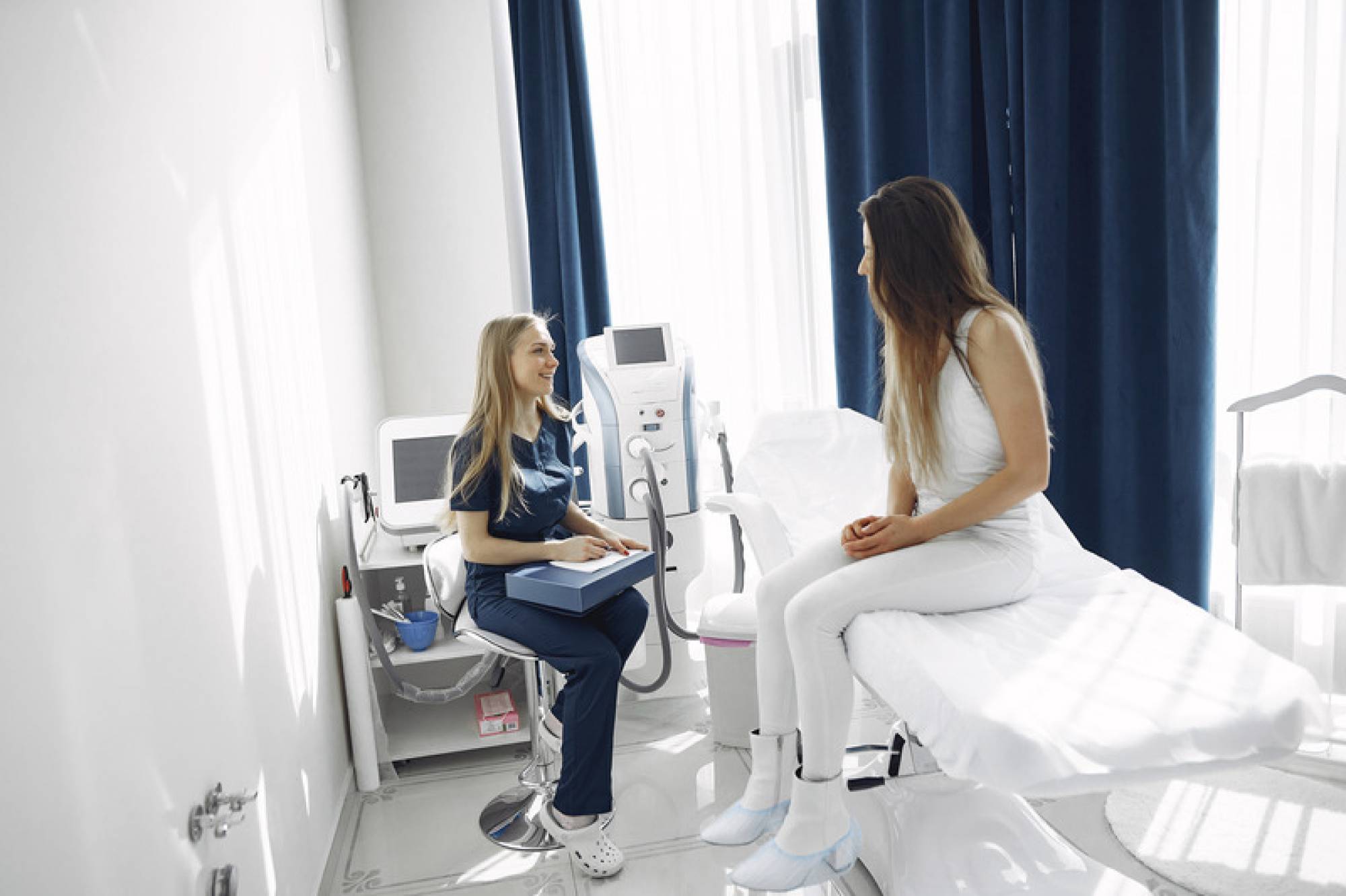 Canva - Woman in Blue Scrub Suit Helping Woman Sitting on Bed